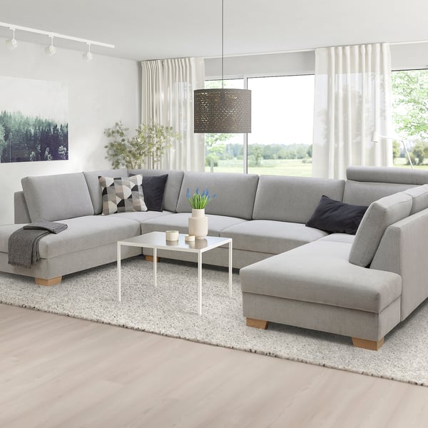 Modern grey l-shaped sofa set, minimalist design, large size, with cushions, coffee table, rug, and plants.