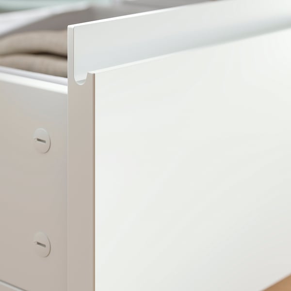 Close-up of white STORKLINTA bed frame with drawers and metal rail for underbed storage.