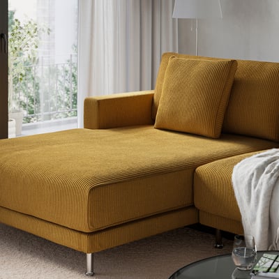 Yellow sectional sofa by window, plush cushions, metal legs, grey throw.