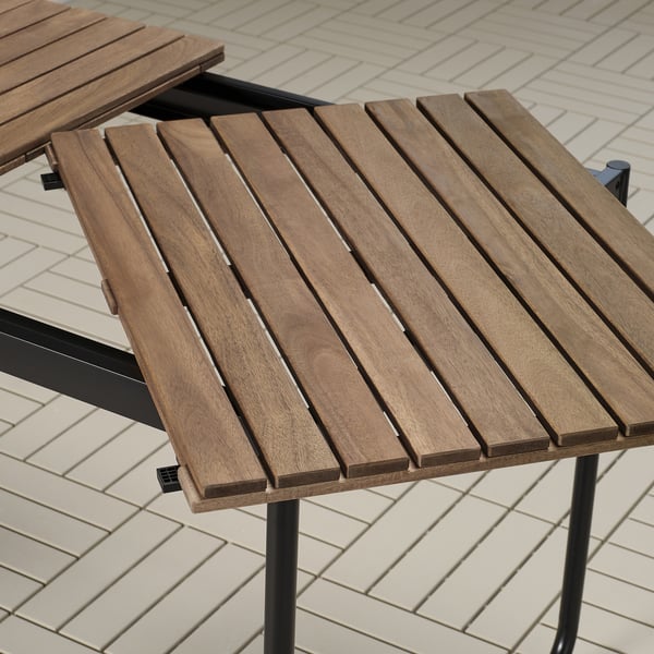 Wooden outdoor table with slatted top and black metal legs, designed for durability and easy storage.