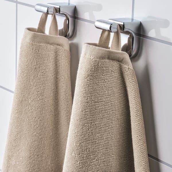 Two beige towels hang neatly on chrome hooks. Showing absorbency and quick drying stripes in the fabric.
