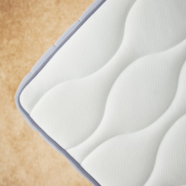 Close-up of VÅGSTRANDA mattress, white, with wavy foam layers for comfort.