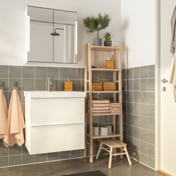 Modern bathroom with birch shelves, towels, plants, and vanity. Blush towels, grey rug, serene atmosphere with gray-tiled walls.