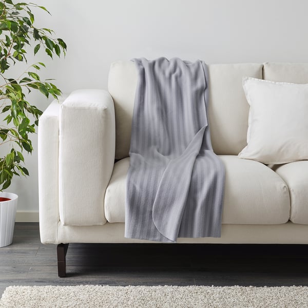 A cosy fleece throw blanket casually draped over a cream-colored sofa, ready for use.