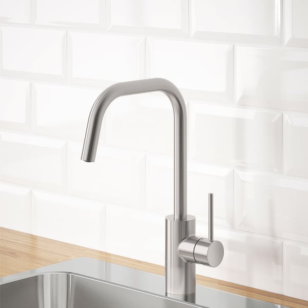Robinet de cuisine moderne, acier inoxydable, comptoir en bois, dosseret en tuiles blanches, économe en eau.