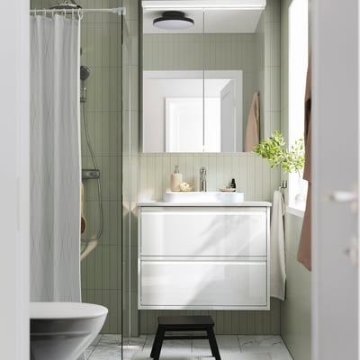 Salle de bain blanche moderne avec vasque ÄNGSJÖN brillant, lavabo en marbre et douche en verre élégant. Personne debout.