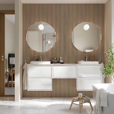 Salle de bain moderne avec meuble blanc ÄNGSJÖN, miroirs ronds, lavabos en marbre, détails en bois et lignes épurées.