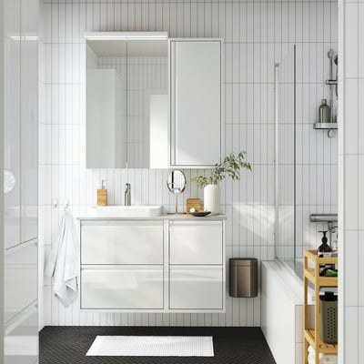 Salle de bain blanche moderne avec grand meuble ÄNGSJÖN, lavabo, miroir, poubelle noire, serviettes, plante et chariot.