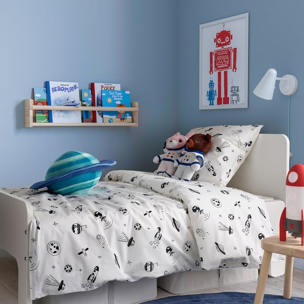 Chambre douillette pour enfants sur le thème de l’espace avec literie d’astronaute, jouets en peluche, livres et art robotique.