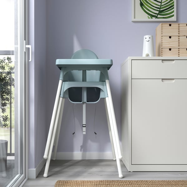 Chaise haute bleu clair avec pieds blancs, facile à assembler, portable, sûre avec ceinture de sécurité et bords anti-déversement.