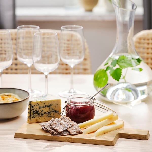 Set de table avec planche à découper en bambou APTITLIG, fromage, craquelins, verres et carafe.