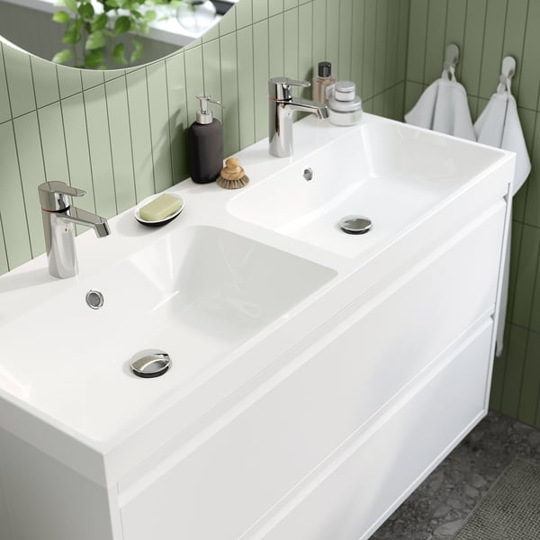 Lavabo de salle de bain moderne avec robinets chromés, porte-savon intégré et trop-plein. Design blanc et élégant avec surface en marbre concassé.