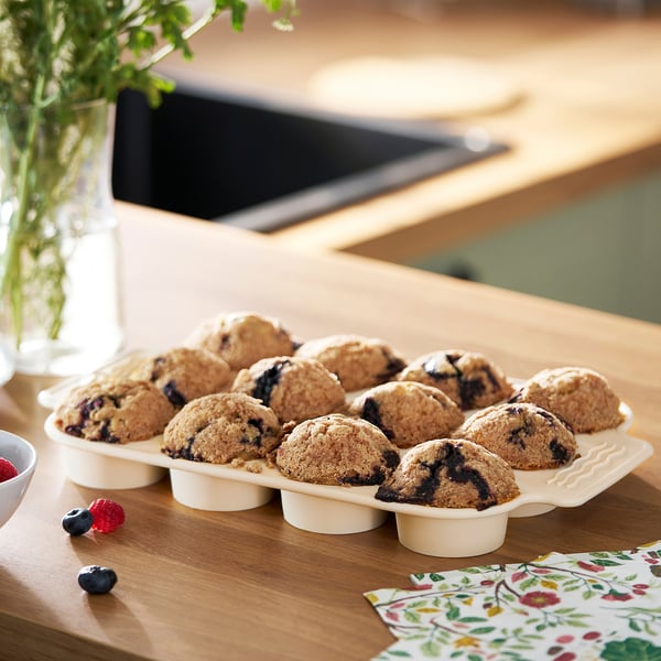 Plateau de muffins aux myrtilles posé sur une table en bois à côté de serviettes et de baies fraîches.