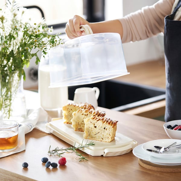 La personne montre des tranches de gâteau sur une table en bois avec des assiettes et des baies.