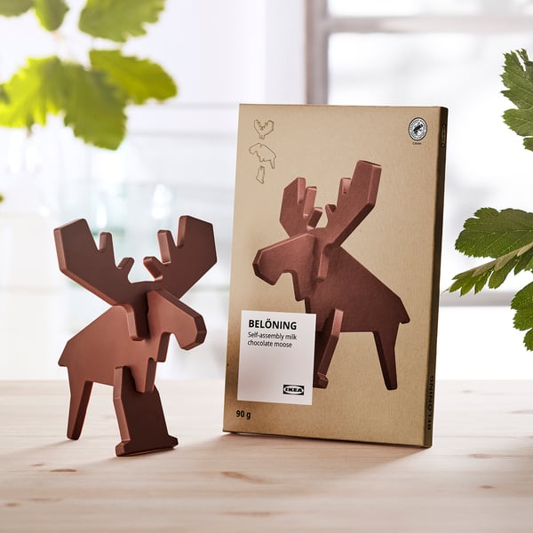 Chocolat brun en forme d’orignal à côté de son emballage, posé sur une table en bois.