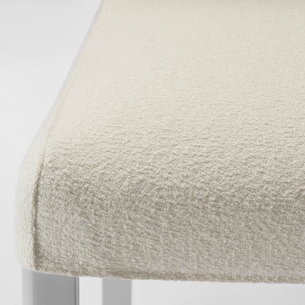Chaise rembourrée blanc cassé avec un tissu lisse, probablement fabriquée à partir de matériaux recyclés. Montre un design épuré et moderne.