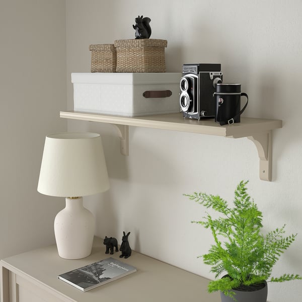 Étagère BERGSHULT avec paniers, appareil photo, sac, lampe, magazine et plante. Nombre de caractères : 49