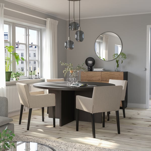 Salle à manger moderne avec table BERGSHYTTAN, chaises beiges, lumières suspendues, grand miroir, lumière naturelle.
