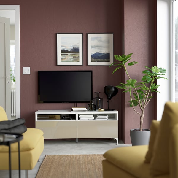 Salon moderne avec des murs violets, une télévision à écran plat sur un meuble TV BESTÅ crème, des sièges jaunes et des plantes vertes.