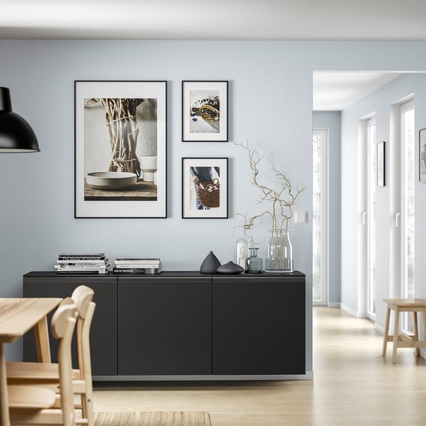Salon moderne avec unité de rangement BESTÅ noire, parquet clair, art minimaliste et murs gris clair à la décoration minimaliste.