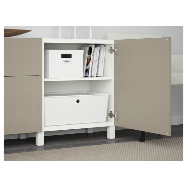 Buffet BESTÅ blanc avec portes ouvertes révélant une boîte de rangement, des livres et des étagères réglables. Tiroir intégré avec ouvre-poussoir en dessous.