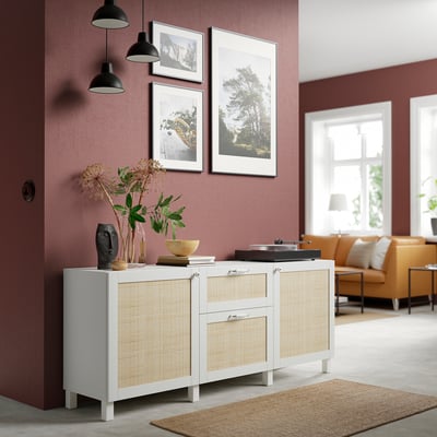Salon moderne avec murs rouges, buffet BESTÅ blanc et canne, suspensions rustiques, photos encadrées. Un canapé orange et un tapis en jute sont visibles.