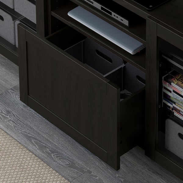 Meuble à tiroirs en bois noir avec compartiments ouverts, pouvant contenir un ordinateur portable, des bacs de rangement et des livres, mettant en valeur une organisation polyvalente.