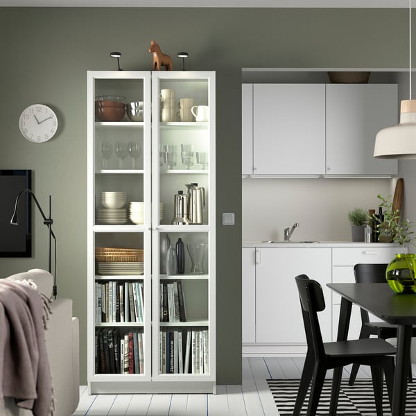 Salon moderne avec bibliothèque BILLARD, mur vert, chaises noires.