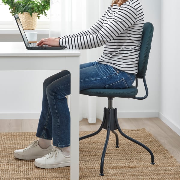 Personne assise dans une chaise pivotante, tapant sur un ordinateur portable au bureau.
