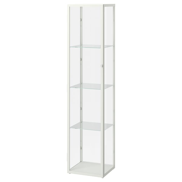 Une armoire à portes vitrées ikea BLÅLIDEN blanche. Il est mince, haut, avec quatre étagères en verre pour exposer soigneusement les articles.