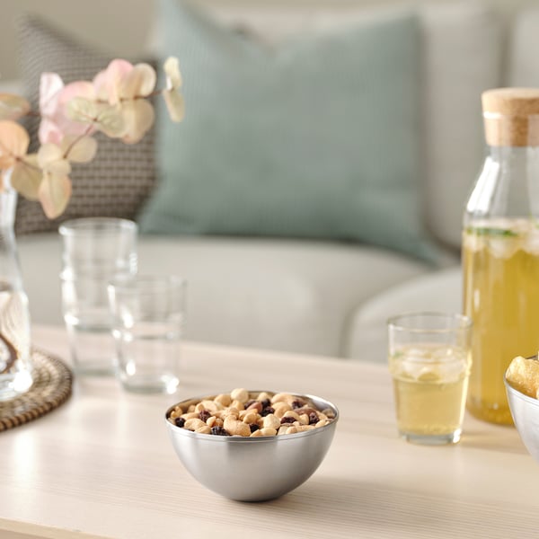 Bol en acier inoxydable avec des noix sur la table, entouré de verres et de limonade.