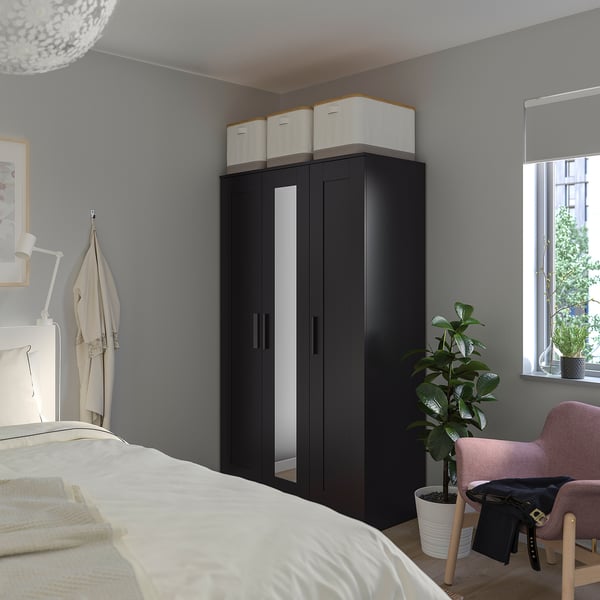 Armoire BRIMNES noire avec miroir dans la chambre.