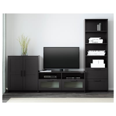 Meuble TV moderne avec écran plat, tiroirs, étagères, placards noirs, bibliothèque avec décor et livres.