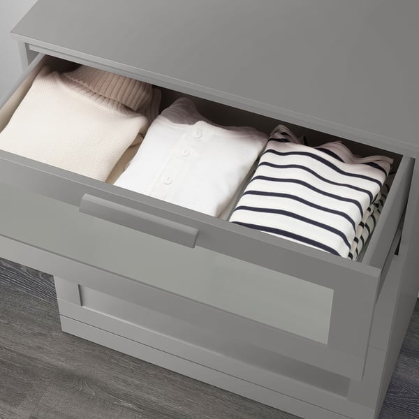 Ouvrez le tiroir de la commode gris révélant des vêtements soigneusement pliés.