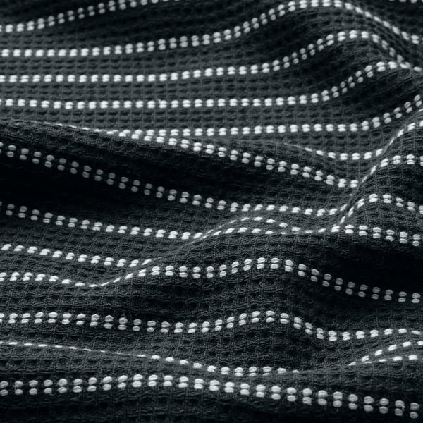 Serviette noire avec motif gaufré blanc, surface éponge douce, texture de coton tissé.