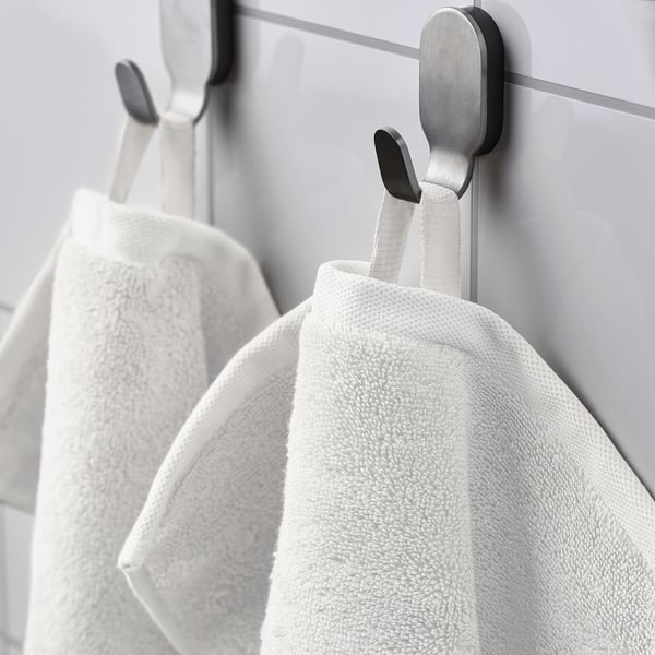 Serviettes sur crochets modernes contre mur carrelé.