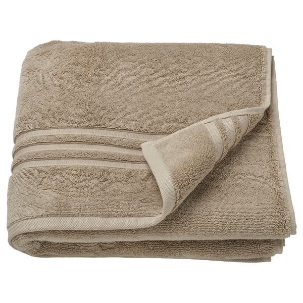 Serviette BROKGLIM, beige, coton biologique, pliée avec une bordure décorative.