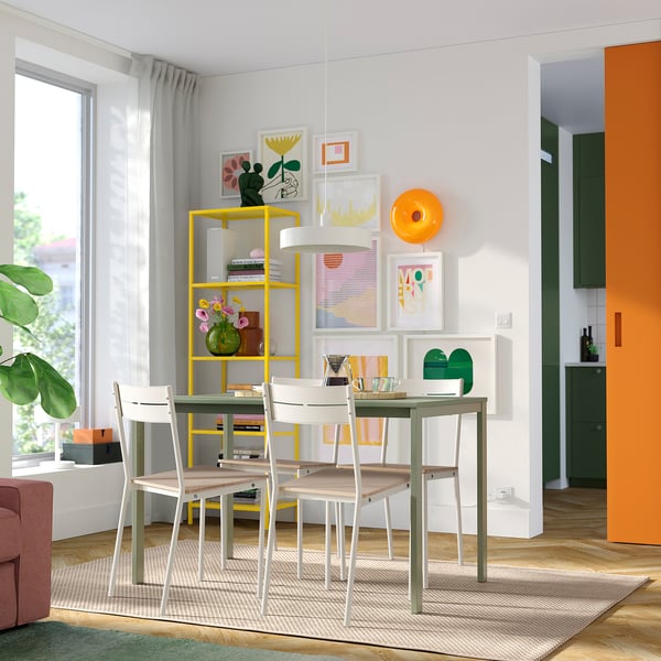 Salle à manger moderne avec chaises BUSLÄTT, étagère jaune et mur de galerie d’art.