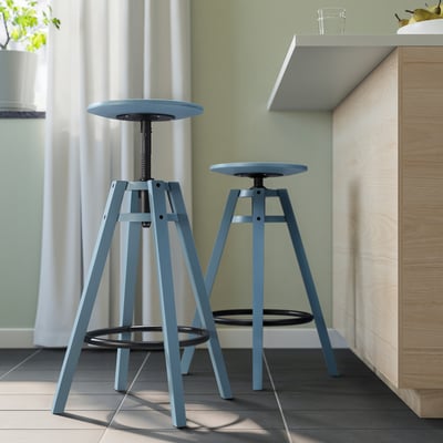 Deux tabourets DALFRED bleus sous comptoir, réglables, boiseries, rideaux blancs.