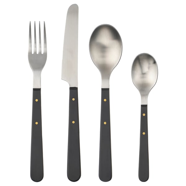 Set de couverts DOFTSKÖLD en quatre pièces en noir avec des accents dorés, doté de poignées en acier inoxydable et d’un design classique.