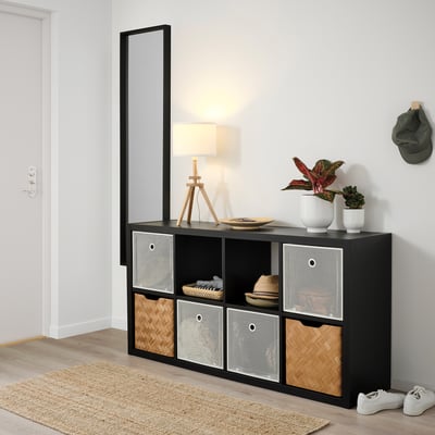 Étagère Kallax avec boîtes DRÖNJÖNS. Lampe, plantes, chapeau et baskets exposés.