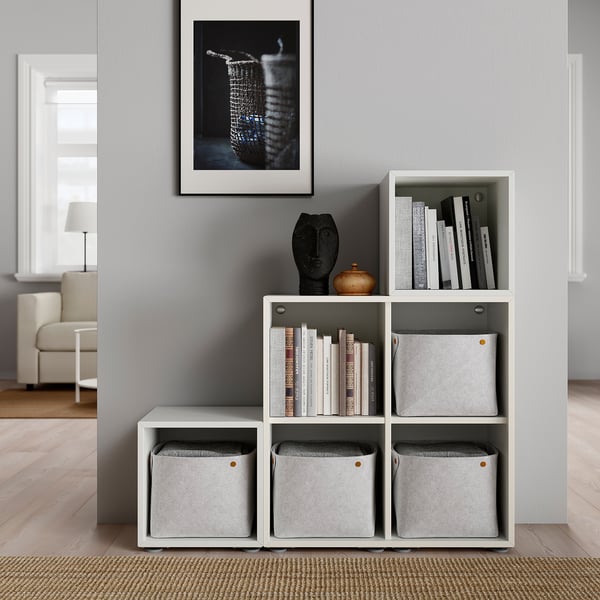 Étagère cube blanc moderne avec bacs gris, objets décoratifs et livres ; Art minimaliste sur mur gris.