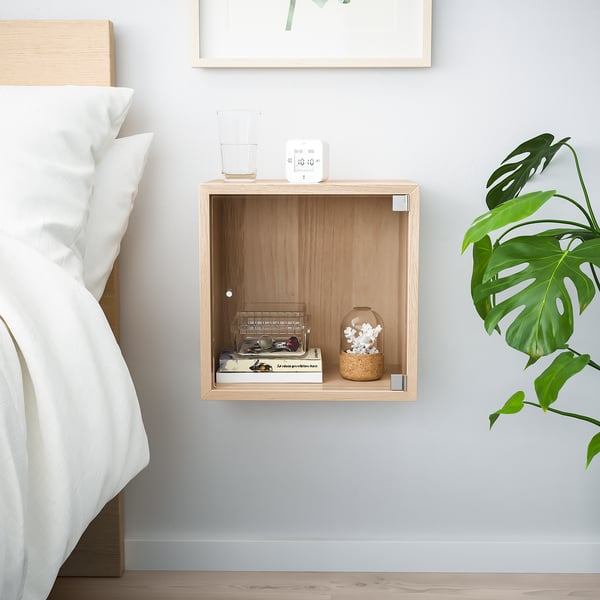 Chambre minimaliste avec étagère flottante en bois, décor blanc et plante verte.