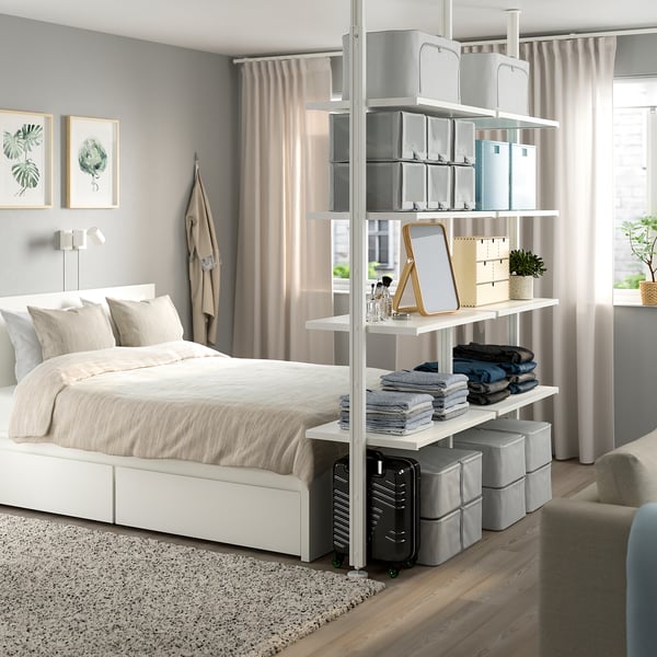 Chambre moderne avec rangement ELVARLI, lit haut, grandes fenêtres et plantes vertes.