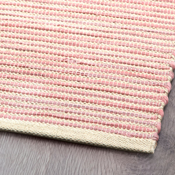 Tapis tissé à la main en rose pastel et beige, démontrant un savoir-faire de haute qualité et un design unique.