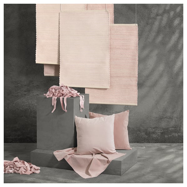 Tapis et coussins roses tissés à la main sur blocs gris. Coton naturel, design unique.
