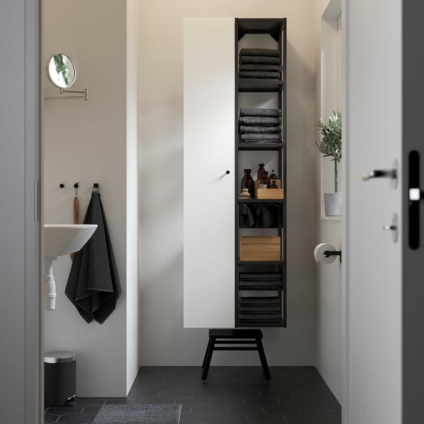 Salle de bain moderne avec un grand espace de rangement en métal noir, serviettes, lavabo et carreaux sombres.