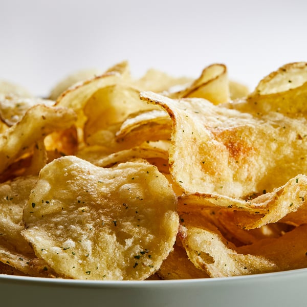 Un bol de chips de pommes de terre rustiques, légèrement assaisonnées, de couleur dorée et légèrement épaisses. Parfait pour grignoter.