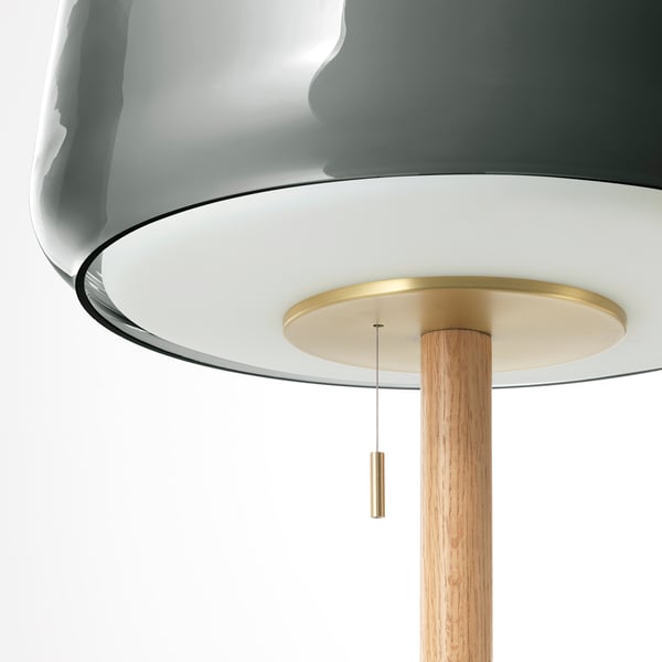 Lampe élégante avec abat-jour en verre gris, accents en laiton et base en bois. Met en valeur l’artisanat et la qualité.