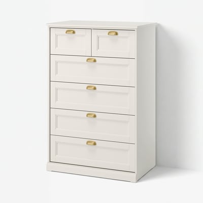 Une commode blanche FÅGELFJÄLLET, avec six tiroirs avec poignées en laiton. C’est une commode haute et rectangulaire avec un design classique et travaillé.